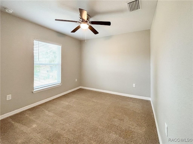 carpeted spare room featuring ceiling fan, visible vents, and baseboards