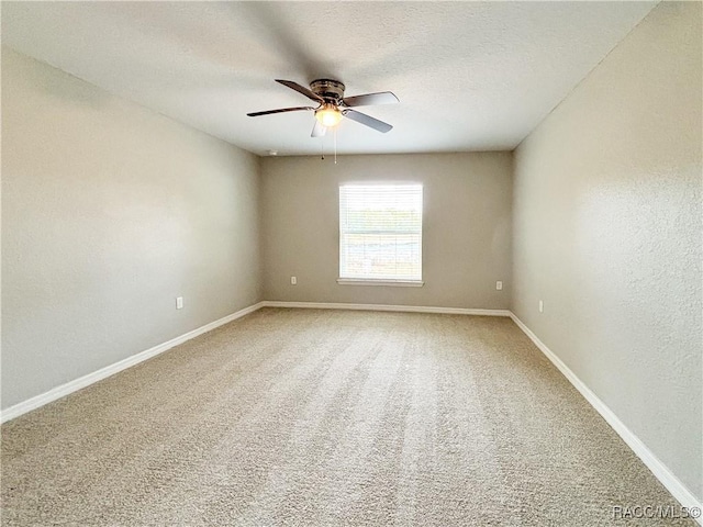 carpeted empty room with ceiling fan, a textured ceiling, and baseboards