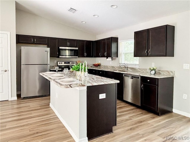 kitchen featuring a center island, visible vents, appliances with stainless steel finishes, vaulted ceiling, and dark brown cabinetry