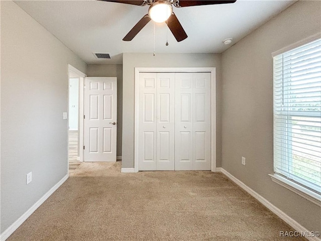 unfurnished bedroom with light carpet, baseboards, visible vents, and a closet