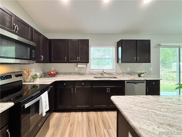 kitchen with light wood finished floors, appliances with stainless steel finishes, a wealth of natural light, and a sink