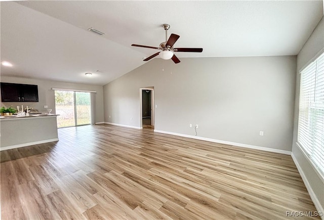 unfurnished living room featuring baseboards, visible vents, a ceiling fan, vaulted ceiling, and light wood-style floors