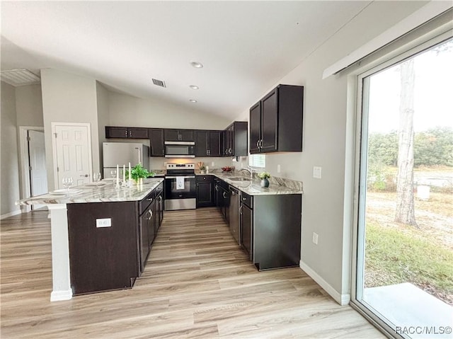 kitchen with visible vents, a kitchen island, vaulted ceiling, stainless steel appliances, and a sink