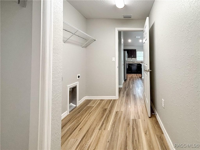 clothes washing area with light wood finished floors, visible vents, hookup for an electric dryer, laundry area, and baseboards