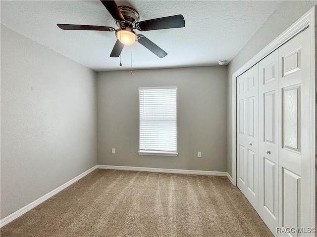 unfurnished bedroom featuring carpet floors, a closet, ceiling fan, a textured ceiling, and baseboards