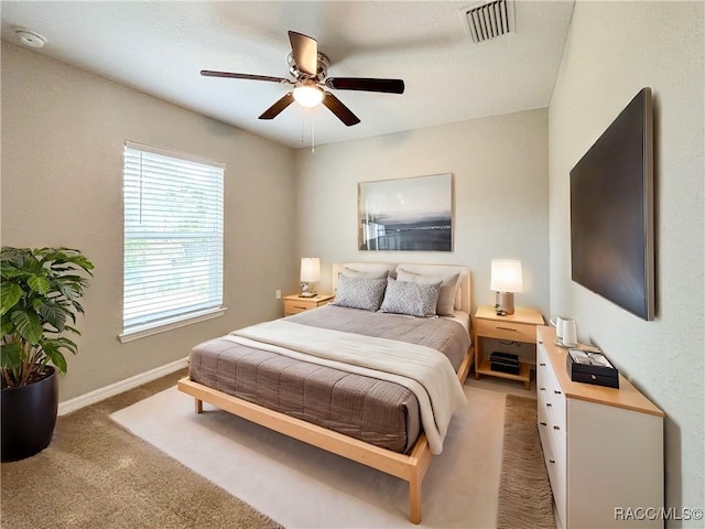 carpeted bedroom with a ceiling fan, visible vents, and baseboards