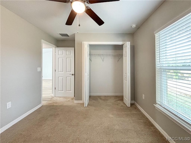 unfurnished bedroom featuring a closet, light colored carpet, visible vents, and baseboards