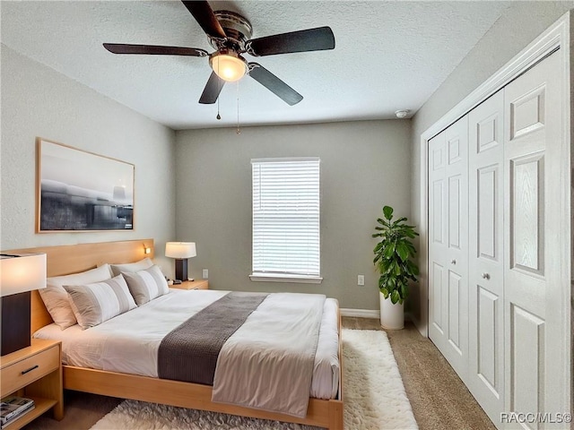 bedroom with baseboards, light colored carpet, ceiling fan, a textured ceiling, and a closet