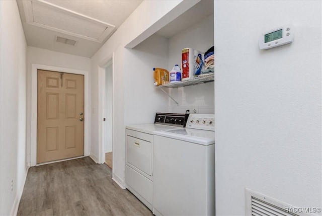 laundry area featuring washer and dryer, laundry area, light wood-style flooring, attic access, and visible vents