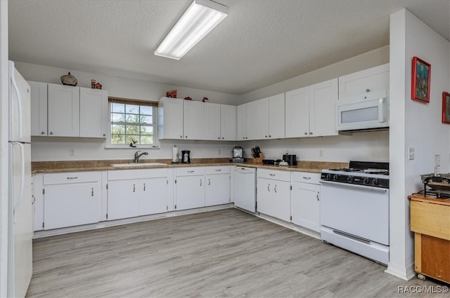 kitchen with white appliances, a textured ceiling, white cabinets, a sink, and light wood-style flooring