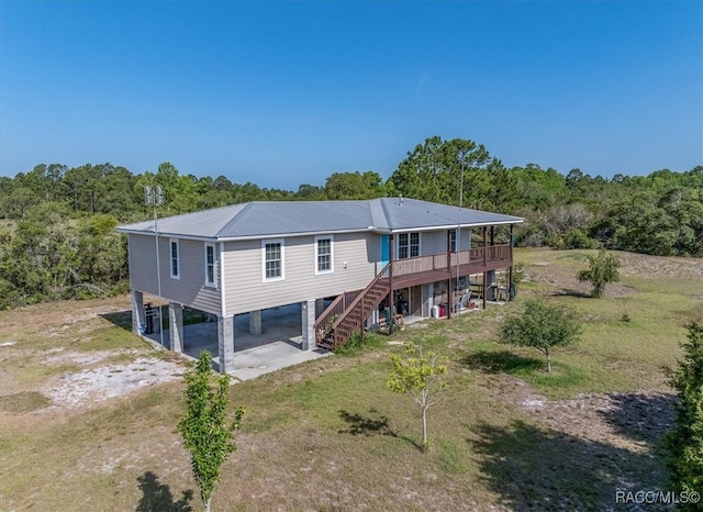 back of property with a deck, dirt driveway, metal roof, stairway, and a carport