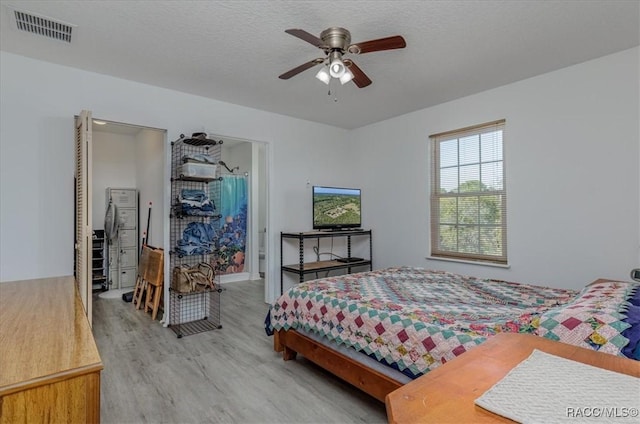 bedroom with light wood-style floors, a ceiling fan, and visible vents