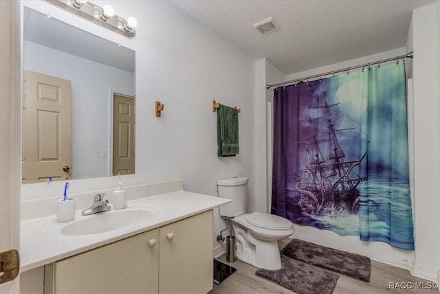 bathroom with toilet, visible vents, wood finished floors, and vanity
