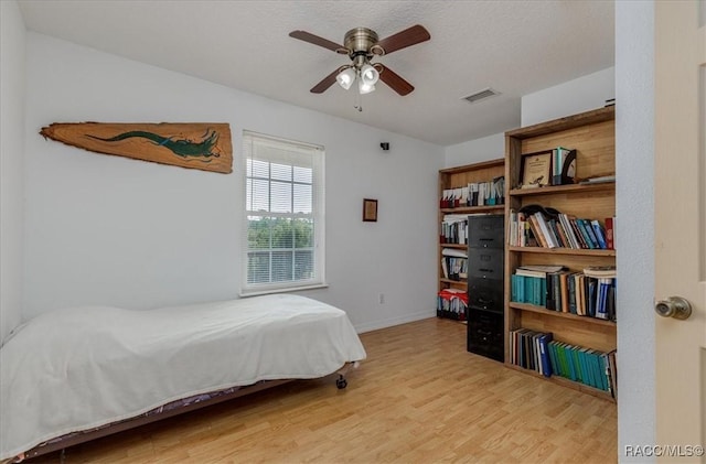 bedroom with visible vents, a ceiling fan, baseboards, and wood finished floors