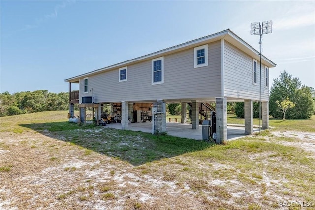 rear view of property with stairway, central air condition unit, and a carport