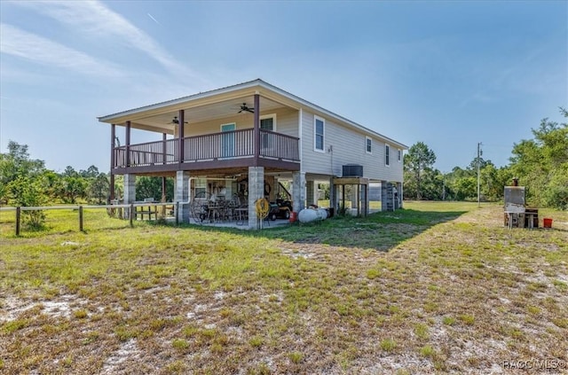 rear view of property with a ceiling fan, a deck, fence, a yard, and a patio