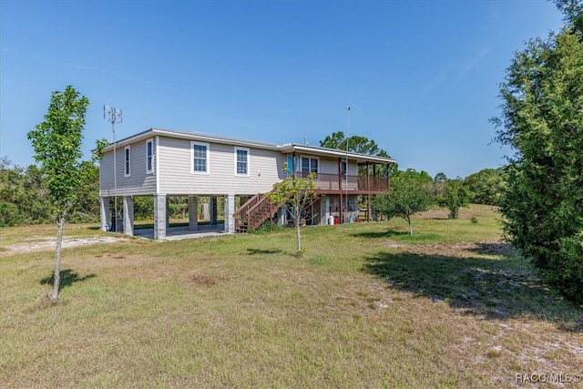 back of house with stairway, a yard, a wooden deck, and a carport