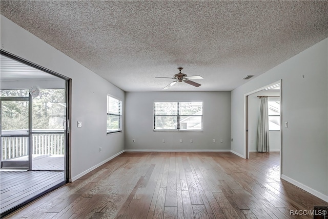 unfurnished room with ceiling fan, light wood-type flooring, a textured ceiling, and a wealth of natural light