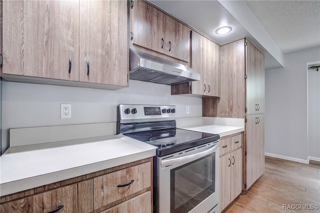 kitchen featuring a textured ceiling, electric range, light hardwood / wood-style floors, and exhaust hood