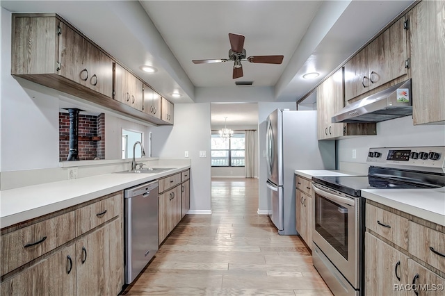 kitchen featuring sink, light hardwood / wood-style floors, ceiling fan with notable chandelier, and appliances with stainless steel finishes