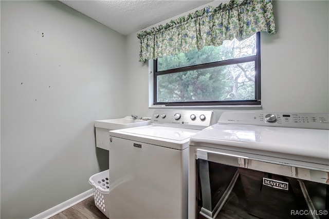 laundry area with a textured ceiling, washing machine and dryer, and dark hardwood / wood-style flooring