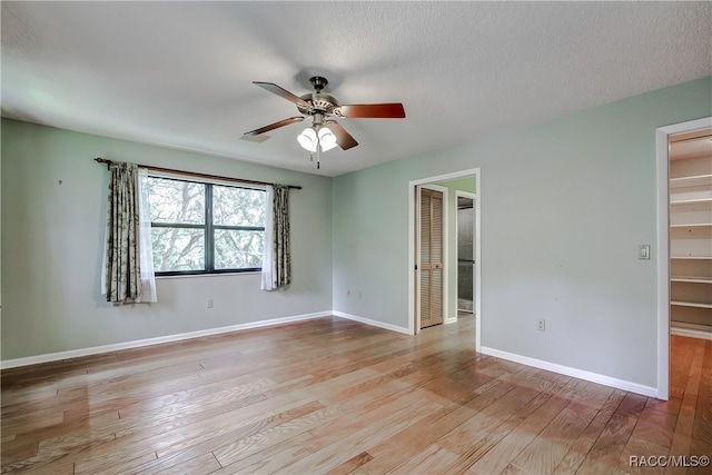 empty room with ceiling fan, light hardwood / wood-style flooring, and a textured ceiling