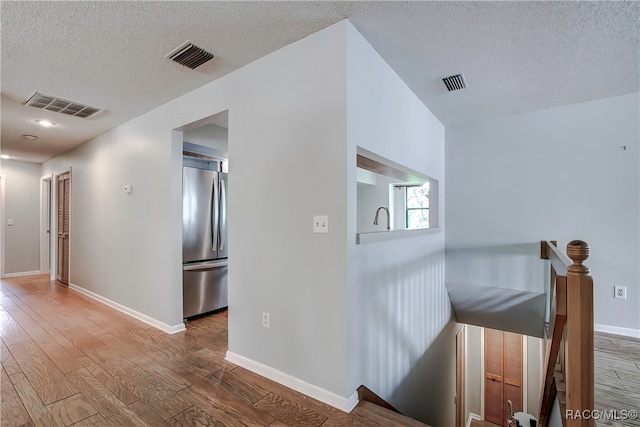 hall with light hardwood / wood-style flooring and a textured ceiling