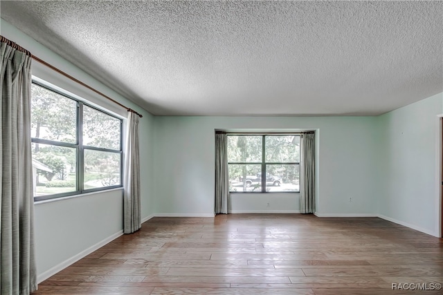 spare room featuring a textured ceiling and light hardwood / wood-style floors