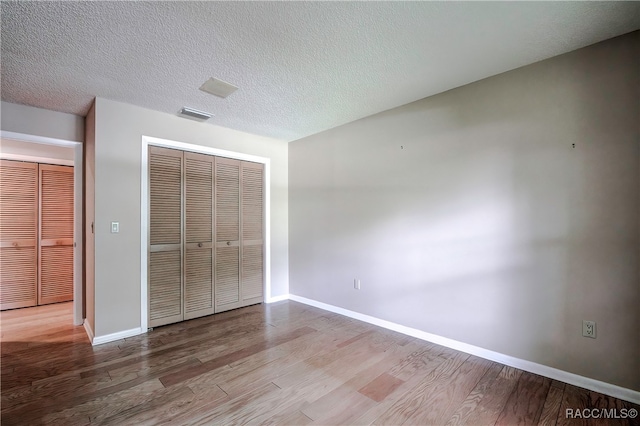 unfurnished bedroom with light hardwood / wood-style floors, a textured ceiling, and a closet