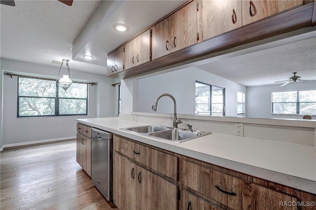 kitchen with light wood-type flooring, stainless steel dishwasher, ceiling fan, sink, and hanging light fixtures