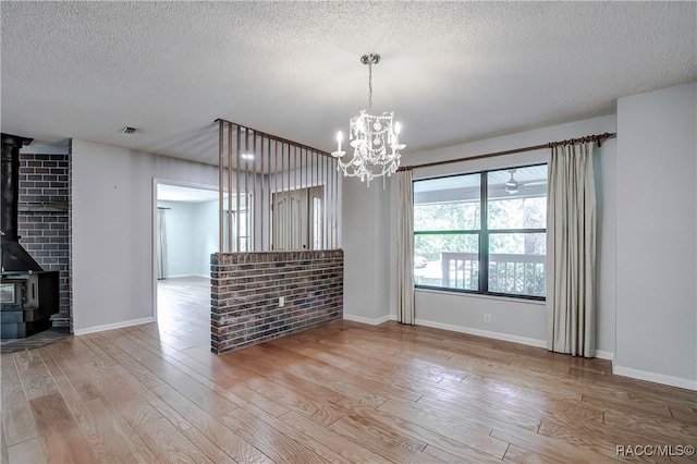 unfurnished dining area featuring a wood stove, light hardwood / wood-style floors, and a textured ceiling