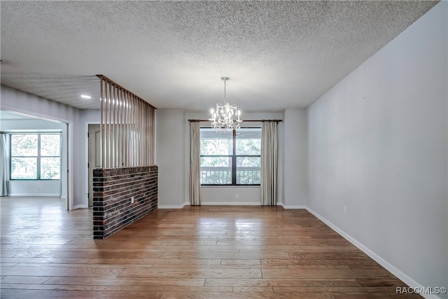 spare room featuring hardwood / wood-style flooring, a textured ceiling, and a chandelier