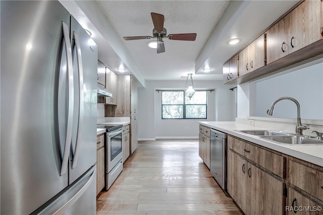 kitchen with sink, light hardwood / wood-style flooring, ceiling fan, decorative light fixtures, and stainless steel appliances