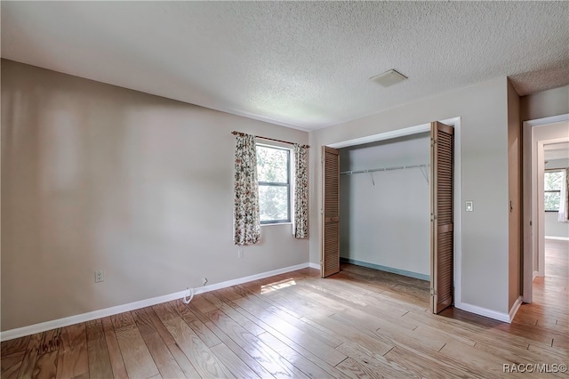 unfurnished bedroom featuring a textured ceiling, light hardwood / wood-style flooring, and a closet