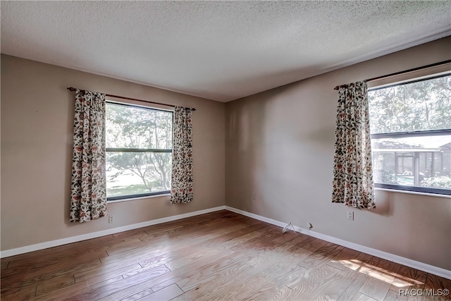 unfurnished room featuring light hardwood / wood-style floors and a textured ceiling