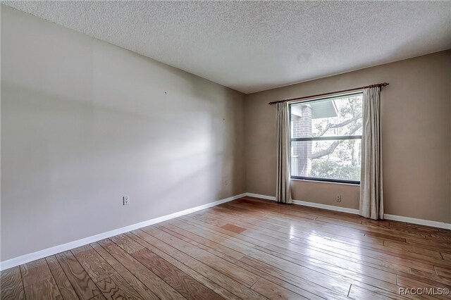 empty room featuring a textured ceiling and light wood-type flooring