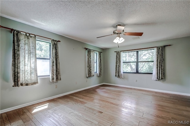 unfurnished room with a healthy amount of sunlight, a textured ceiling, and light hardwood / wood-style floors