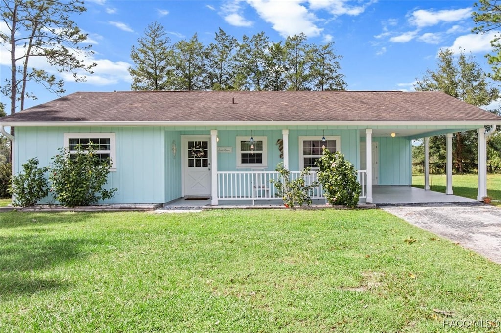 ranch-style home featuring a porch, a front yard, and a carport