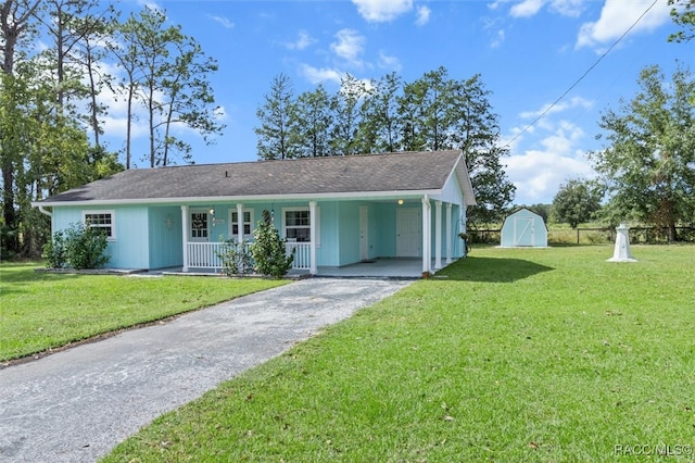 ranch-style house featuring covered porch, a front lawn, a storage unit, and a carport