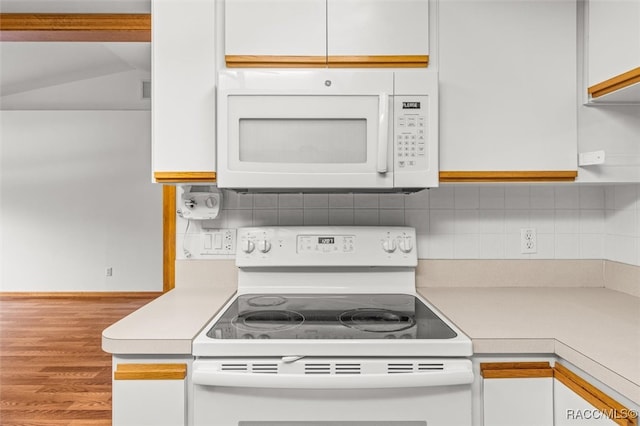 kitchen featuring backsplash, white cabinetry, wood-type flooring, and white appliances