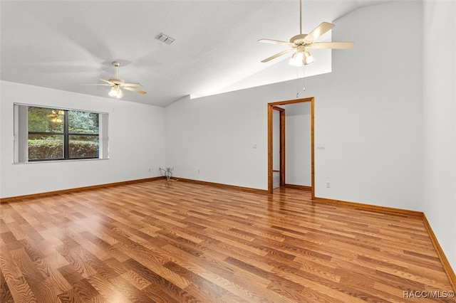 empty room with a textured ceiling, ceiling fan, light hardwood / wood-style flooring, and lofted ceiling