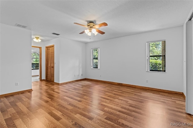 spare room featuring a healthy amount of sunlight, wood-type flooring, and a textured ceiling