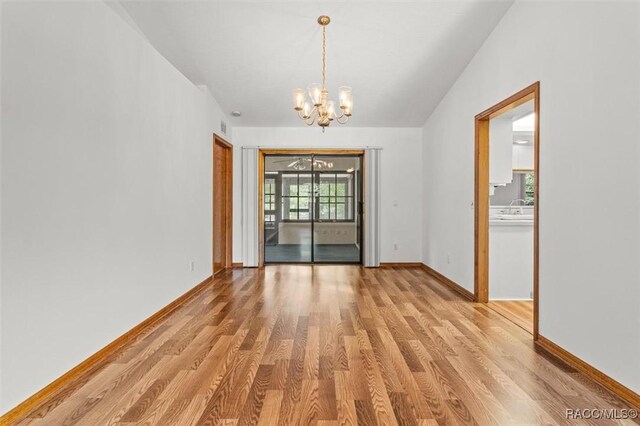 2494 W Axelwood Dr, Beverly Hills, FL 34465 - empty room featuring light wood-type flooring, a notable chandelier, lofted ceiling, and baseboards