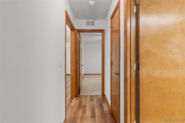 2494 W Axelwood Dr, Beverly Hills, FL 34465 - hallway with baseboards, a textured ceiling, visible vents, and wood finished floors
