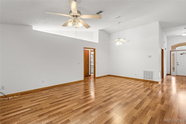 empty room with a textured ceiling, light wood-type flooring, high vaulted ceiling, and ceiling fan