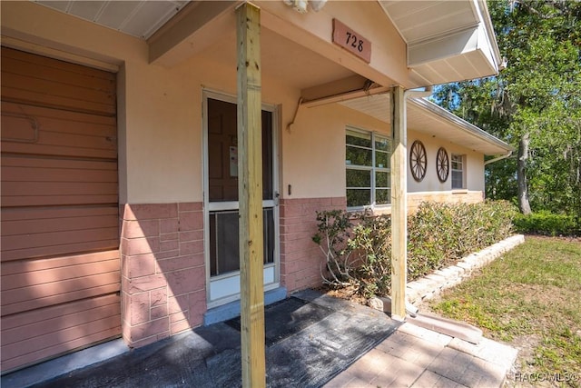 728 S Juniper Way, Inverness, FL 34450 - view of exterior entry featuring stucco siding and brick siding