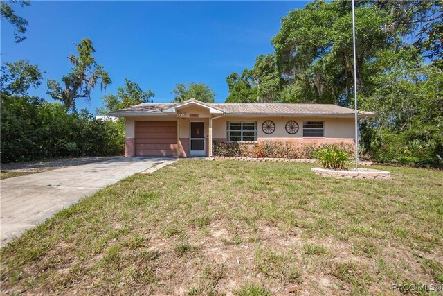 728 S Juniper Way, Inverness, FL 34450 - single story home with an attached garage, a front yard, driveway, stucco siding, and metal roof