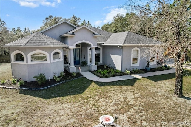 view of front of house featuring a front lawn, roof with shingles, and stucco siding