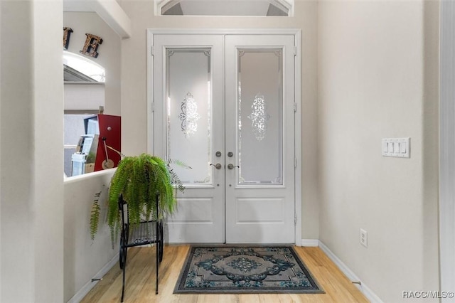 foyer featuring baseboards, wood finished floors, and french doors