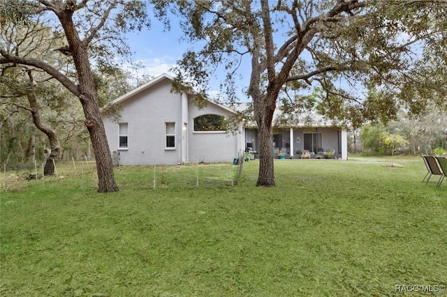 back of house featuring a lawn and stucco siding